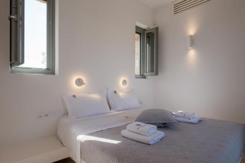 a white bedroom with a bed with towels on it at Bracket House Paros in Prodromos Paros