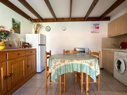 une cuisine avec une table avec des chaises et un réfrigérateur dans l'établissement Maison T3 Mézzanine à 1 km de la plage – Terrasse privée, BBQ, parking, animaux admis, près commerces - FR-1-705-69, aux Mathes