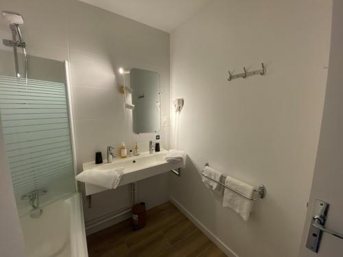 a white bathroom with a sink and a mirror at Logis Hôtel Médiéval, Montélimar Nord in Rochemaure