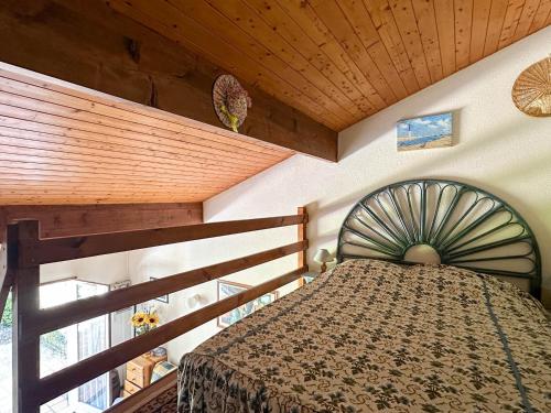 une chambre avec un lit et un plafond en bois dans l'établissement Maison T3 Mézzanine à 1 km de la plage – Terrasse privée, BBQ, parking, animaux admis, près commerces - FR-1-705-69, aux Mathes
