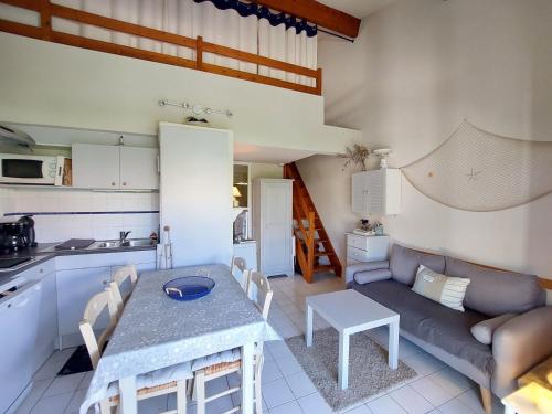 Il dispose d'une cuisine et d'un salon avec un canapé et une table. dans l'établissement Charmante Maisonnette avec Piscine à Proximité du Lac et des Plages de Saint-Palais-sur-Mer - FR-1-550-80, à Saint-Palais-sur-Mer