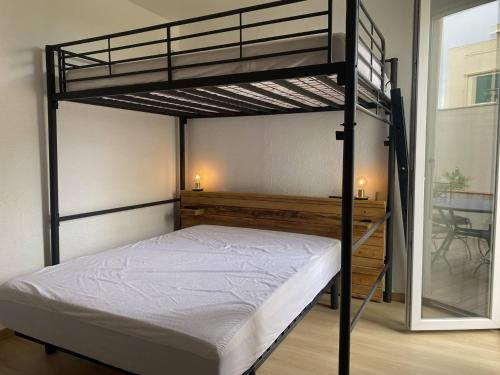 une chambre avec un lit superposé avec des draps blancs dans l'établissement Appartement rénové en bord de mer avec terrasse, accès direct à la plage, parking privé, WIFI - FR-1-782-62, au Barcarès