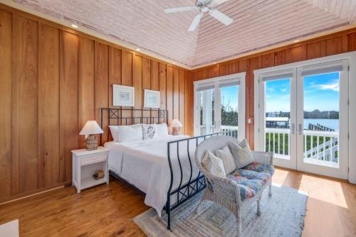 a bedroom with a bed and a chair and windows at Roosevelt Cottage in Captiva