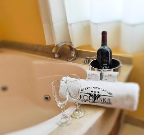 eine Flasche Wein und zwei Weingläser auf einer Badewanne in der Unterkunft Hotel Korianka in Trujillo