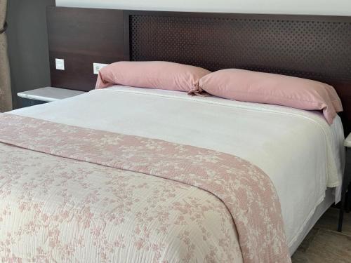 a bed with two pink pillows on top of it at CASA YANGUAS APARTAMENTOS RURALES EN LAUJAR DE ANDARAx in Laujar de Andarax