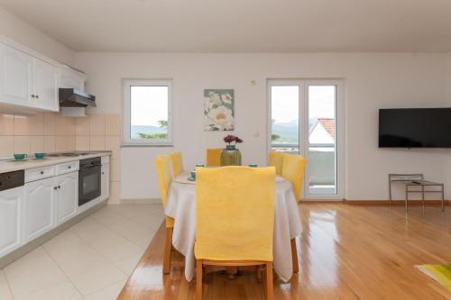 a kitchen and dining room with a table with yellow chairs at Apartman Maria in Imotski