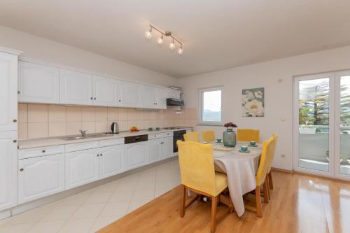 a kitchen with white cabinets and a table with chairs at Apartman Maria in Imotski