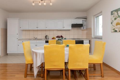 a kitchen with a dining table and yellow chairs at Apartman Maria in Imotski
