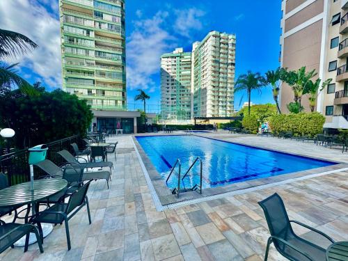 una piscina con mesas, sillas y edificios en Flat Mar Montanha Four Seasons, en Río de Janeiro