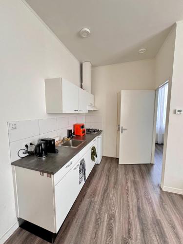 a kitchen with white cabinets and a wooden floor at 86 3City Appartement met Privé parkeerplaats in Enschede