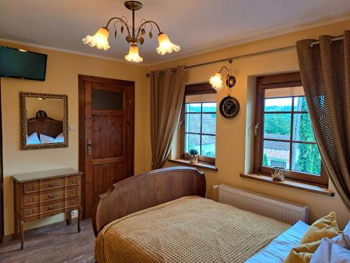 a bedroom with a bed and a dresser and windows at Szachulcowa Zagroda in Ustka