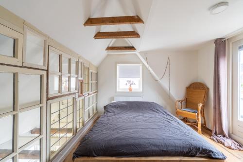 a bedroom with a bed and a window at Stijlvol & lief onthaast-huisje met piano, tv en wifi in Holwerd