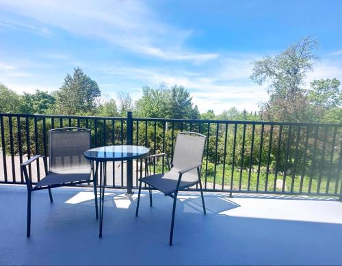 a patio with two chairs and a table and a fence at Le domaine du Sous-Bois in Mont-Blanc