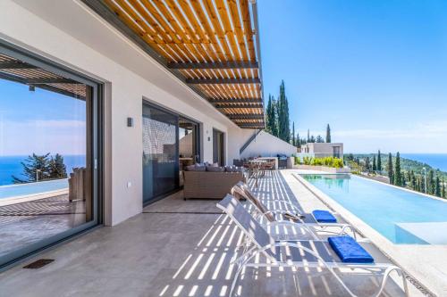 a house with a swimming pool and some chairs at Villa Andromeda Sunset in Tsoukaladhes