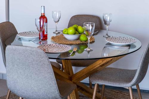 a glass table with a bowl of apples and wine glasses at Villa Andromeda Sunset in Tsoukaladhes