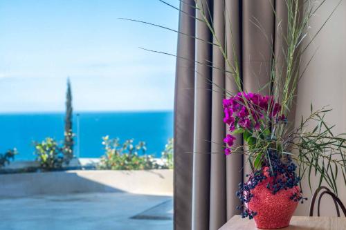 a vase of flowers sitting on a table with the ocean at Villa Andromeda Sunset in Tsoukaladhes