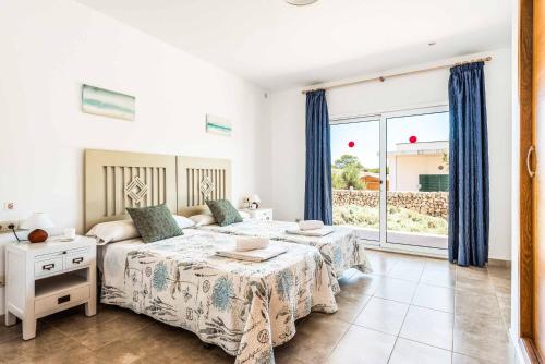 sypialnia z 2 łóżkami i dużym oknem w obiekcie Villa Satalaia w mieście Sant Lluis