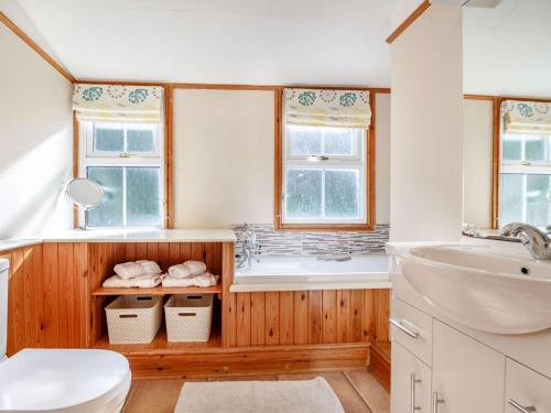 a bathroom with a tub and a sink and two windows at 6 Bed in Harlech 89630 in Harlech