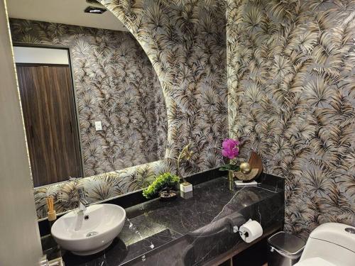 a bathroom with a sink and a toilet and a mirror at A 7 Minutos de San Pedro Lujoso Penthouse in Monterrey
