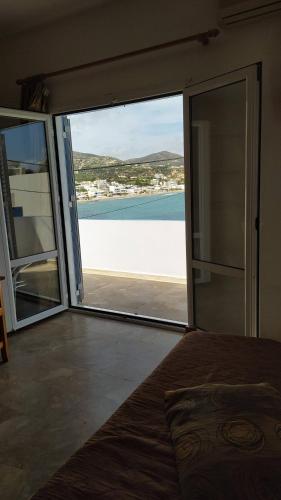 a bedroom with a large glass door with a view of the ocean at Sea View And Mountain View Apartment For 4 People in Makry Gialos