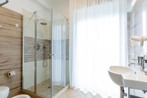 a bathroom with a glass shower and a sink at Hotel Lungomare in Cervia