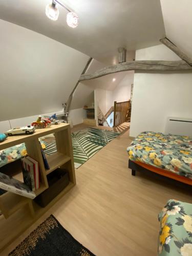 Cette chambre mansardée comprend un lit et un escalier. dans l'établissement Maison spacieuse sur 2 étages complètement rénovée, à Marolles