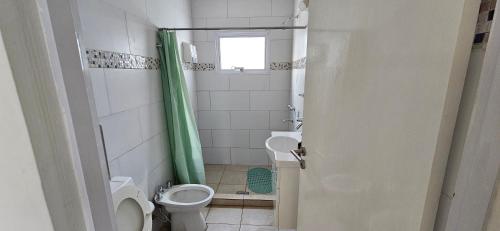 een badkamer met een toilet en een groen douchegordijn bij Manantial Departamentos in Gualeguay