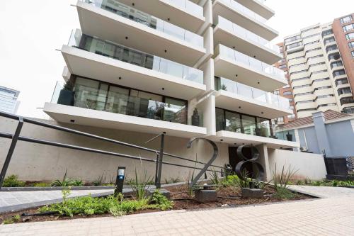 a tall white building with plants in front of it at AT HOME El Golf in Santiago