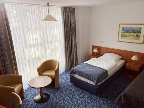 Habitación de hotel con cama, silla y ventana en Hotel Am Weißen Turm, en Bad Neuenahr-Ahrweiler