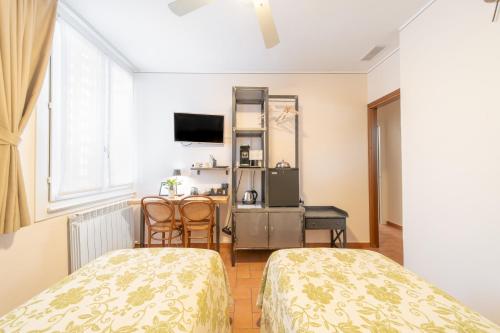 a room with two beds and a table and a television at B&B Osteria dello sperone in Lonate Pozzolo