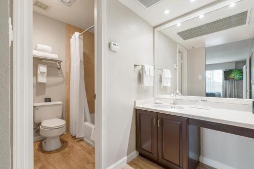 a bathroom with a sink and a toilet and a mirror at Chase Suite Hotel Newark Fremont in Newark