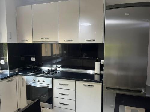 a kitchen with white cabinets and a stainless steel refrigerator at Apartament Qetesia in Çorovodë