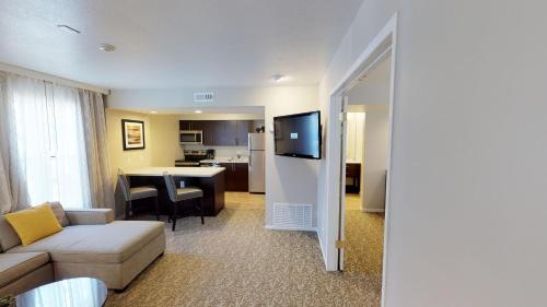 a living room with a couch and a table with a kitchen at Chase Suite Hotel Newark Fremont in Newark