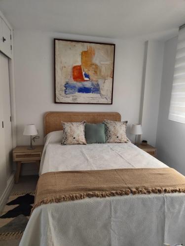 a bedroom with a bed and a painting on the wall at Agradable Dúplex Terraza Virgen del Rocio in Seville