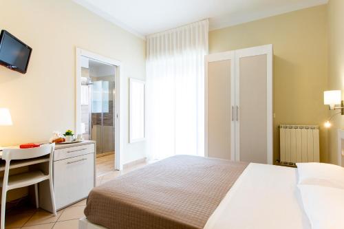 a bedroom with a bed and a desk and a television at Hotel Lungomare in Cervia