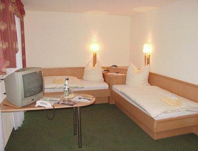 a room with two beds and a desk with a television at Landhotel Rittersgrün in Breitenbrunn