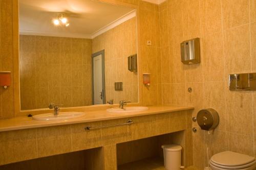 a bathroom with two sinks and a mirror and a toilet at Solar dos Caldeira e Bourbon in Zebras