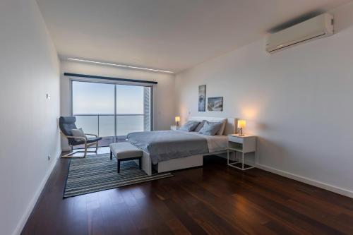 a bedroom with a bed and a chair and a window at Xenon Urban Apartments in Maputo