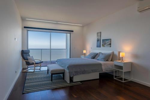 a bedroom with a bed and a chair and a large window at Xenon Urban Apartments in Maputo