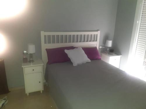 a bedroom with a large bed with purple and white pillows at Casa Adosada in Bormujos