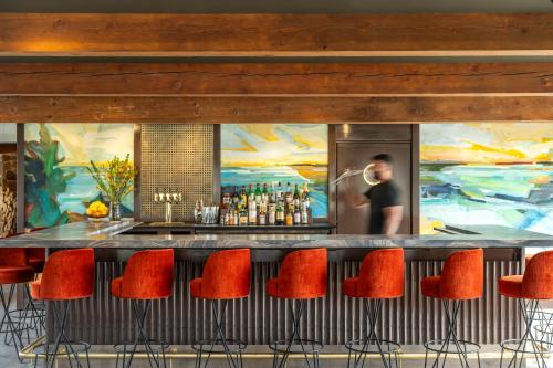 a bar with red chairs and a painting of a man at Otis Harbor Springs in Harbor Springs