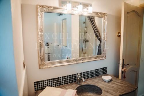 un miroir sur un mur au-dessus d'un lavabo dans la salle de bains. dans l'établissement Mas de l'air, à Noves