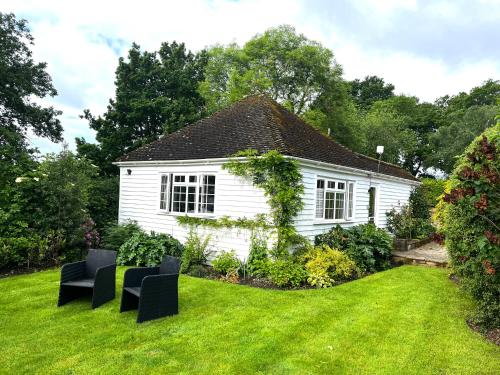 a white house with chairs in a yard at Huntleys Lodge in Ticehurst