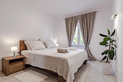 a white bedroom with a bed and a potted plant at Corcyra Nigra Apartment 2 in Blato