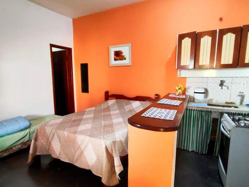 una cucina con una camera arancione con un letto di Suites Americanas Em Jaconé a Jaconé
