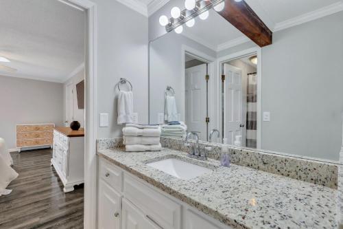 a bathroom with a sink and a large mirror at Penthouse Loft- Balcony Over Downtown Statesboro in Statesboro