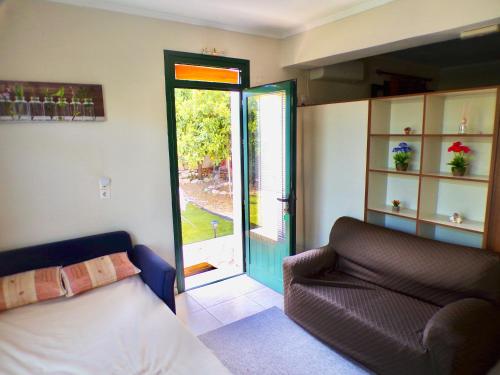 a bedroom with a bed and a couch and a door at Nefeli’s guest house in Nydri