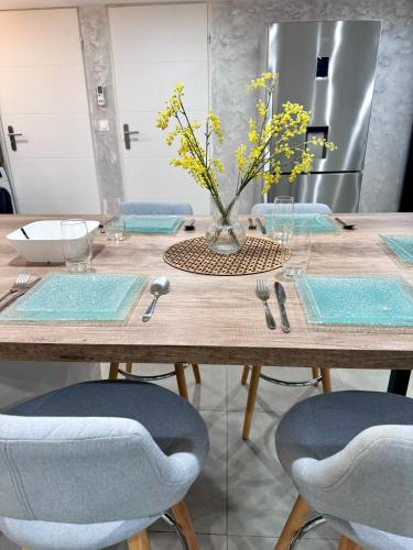 a table with chairs and a vase of flowers on it at Appartement moderne in Bussières-lès-Belmont