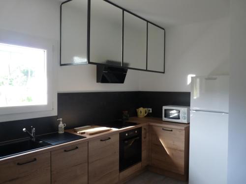 une cuisine avec des armoires en bois et un réfrigérateur blanc dans l'établissement Appartement indépendant dans villa, entre Fréjus et St Raphaël, à Fréjus