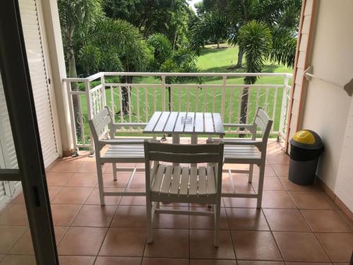 a porch with a table and chairs on a balcony at la Désirade in Sainte-Luce